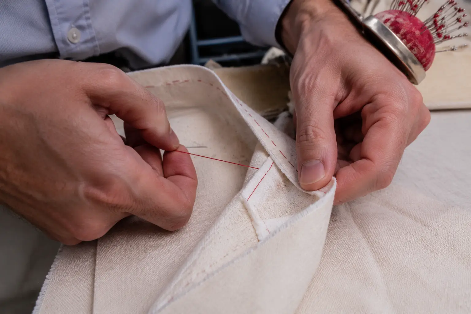 Adult tailor hands constructing a clean seam in cream linen